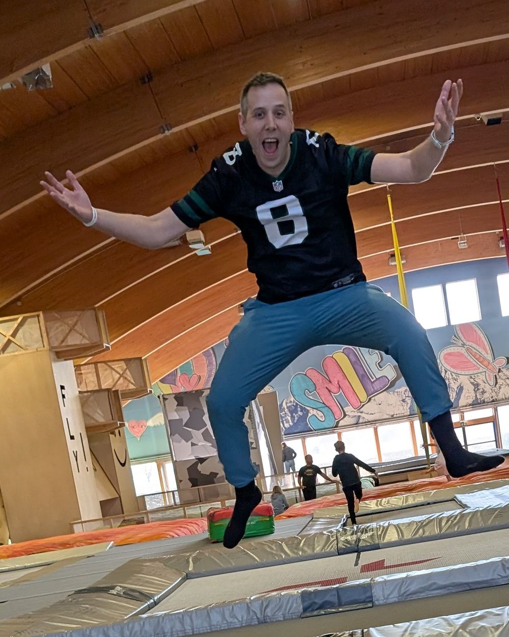 Mikael von Allmen, mitten im Sprung über einem Trampolin, Arme ausgebreitet und lachend